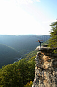 Sarah Chouinard enjoys a late afternoon yoga session standing bow pose, atop the Bosnian Buttress along the rim of the New River Gorge near Fayetteville, WV