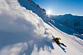 Skifahrer zieht Schneefahne bei Sonnenuntergang hinter sich her, Hochfügen, Zillertal, Österreich