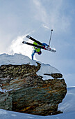 Skifahrer macht Sprung und greift mit Hand in Schnee, Verbier, Schweiz