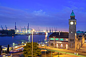 Beleuchtete St. Pauli-Landungsbrücken mit Pegelturm und Hafen im Hintergrund, Landungsbrücken, Hamburg, Deutschland