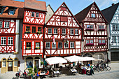 Half-timbered house in the old town with people sitting outside cafes and restaurants, Ochsenfurt, Franconia, Bavaria, Germany