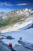 Three persons climbing on snow and rock slabs, Sentiero Roma, Bergell range, Lombardy, Italy