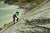 Woman climbing on granite slab, lake in background, Raeterichsboden, Grimsel pass, Bernese Oberland, Switzerland