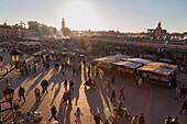 Evening light on the busy square of Place Jemaa el-Fna with the minaret of the Koutoubia Mosque in the distance, UNESCO World Heritage Site, Marrakech, Morocco, North Africa, Africa