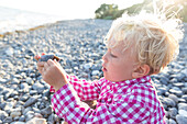Boy (4 years) holding a stone at beach, Klintholm, Mon island, Denmark
