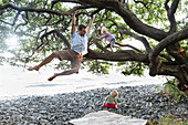 Vater und Kinder spielen in einem Baum am Ostseestrand, Klintholm, Insel Mön, Dänemark