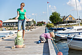 Mutter und Kinder (1-4 Jahre) auf einem Bootssteg im Hafen, Guldborg, Falster, Dänemark