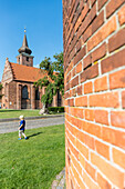 Junge auf einer Wiese, Klosterkirken im Hintergrund, Nyköbing Falster, Falster, Dänemark