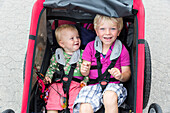 Siblings (1-4 Jahre) sitting in a bicycle trailer, Marielyst, Falster, Denmark