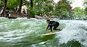 Surfer surfing on the Eisbach in the English Garden, Munich, Upper Bavaria, Bavaria, Germany