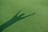 Shadow of golfer raising arms