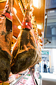 Smoked pork legs hanging on display in butcher's shop