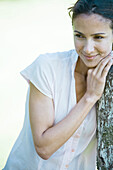 Woman leaning on wooden post, smiling