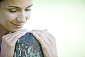 Woman leaning on wooden post, smiling, looking down, close-up