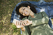 Woman lying on ground text messaging