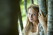 Woman leaning against tree trunk, portrait