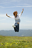 Young woman jumping in midair outdoors, rear view