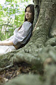 Young woman leaning against tree