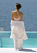 Woman standing overlooking water, bathrobe off shoulders