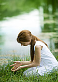 Girl kneeling in grass with hands cupped