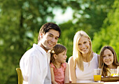 Family sitting at table with juice, outdoors