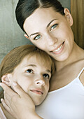 Preteen girl resting head on young woman's chest