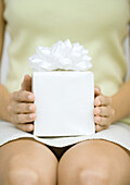 Woman holding present on lap, close-up
