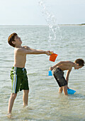 Boys playing in ocean with buckets