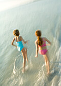Two girls running in surf