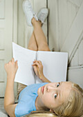 Girl studying, lying on back with legs up