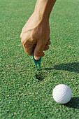 Golfer using divot repair tool on turf, close-up of hand