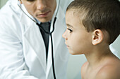 Doctor leaning toward boy with stethoscope