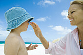 Mother putting sunscreen on child at beach