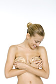 Woman holding silicone implants over breasts, looking down, smiling