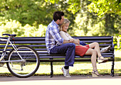 Young couple relaxing together on park bench