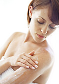 Junge Frau trägt Feuchtigkeitscreme auf den Arm auf, Nahaufnahme