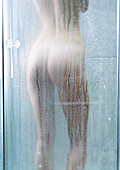 Frau unter der Dusche, Rückansicht.