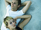 Couple lying on sand, close-up, elevated view