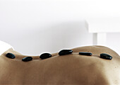 Woman's back with black stones lined up along spine, close-up