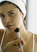 Young woman applying make-up with blush brush