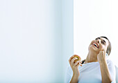Woman holding apple and laughing, on phone