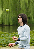 Young man juggling apples outdoors