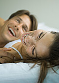 Couple lying in bed, laughing