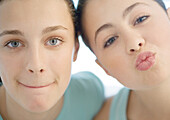 Two preteen girls, one puckering, the other pursing lips