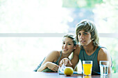 Couple in exercise clothes sitting at table with juice and fruit