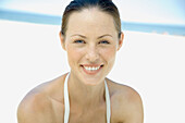 Woman on beach, smiling at camera, head and shoulders
