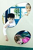 Children on playground equipment, smiling at camera