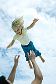 Man throwing little girl into the air, low angle view