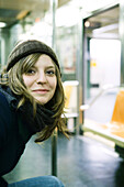 Young woman riding subway, smiling at camera