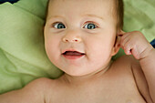 Baby pulling on ear, smiling